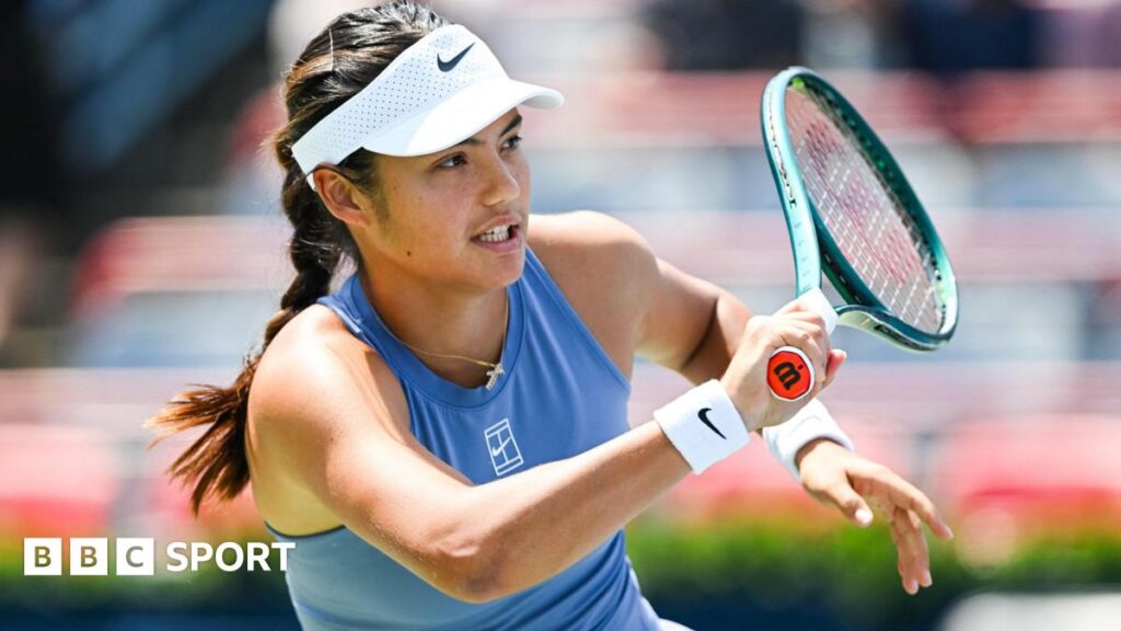 Emma Raducanu holds up a tennis racquet
