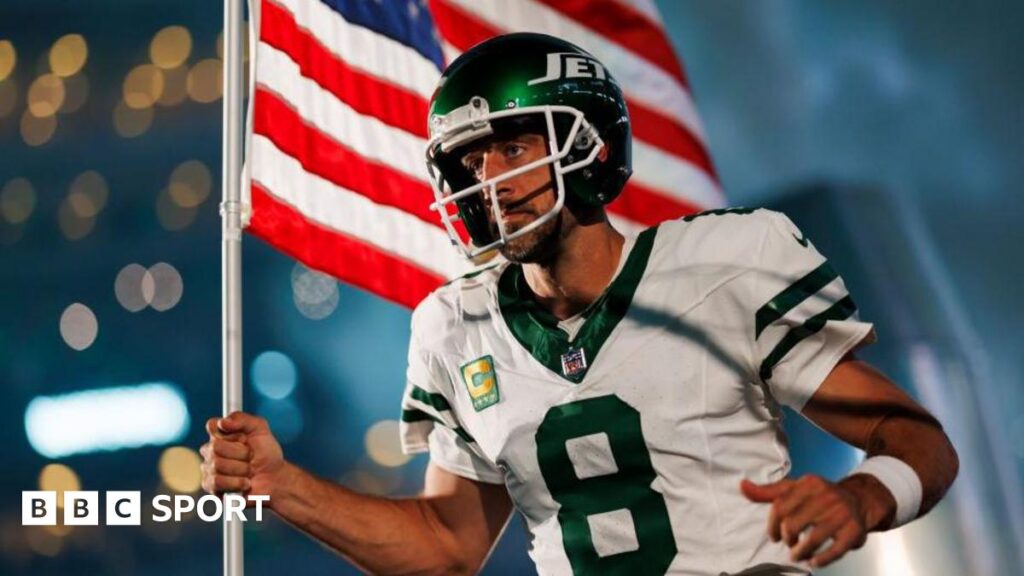 Aaron Rodgers runs onto the field for his New York Jets debut carrying an American flag